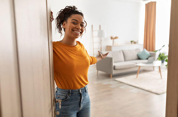 Woman standing at door welcoming guest into large living room.