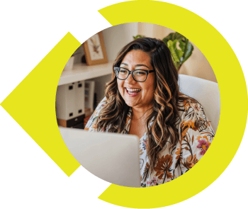 Happy lady smiling at laptop screen at desk.