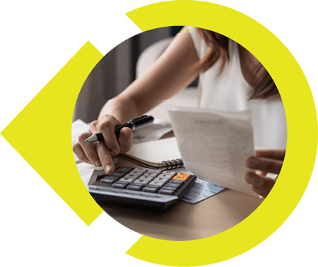 Woman sitting at desk working on calculator to calculate receipts in hand.