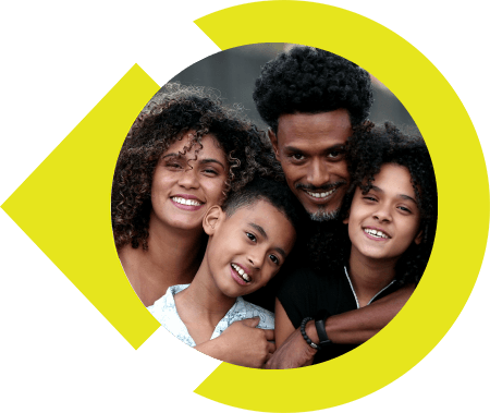 Family of four with arms around one another smiling for photo.