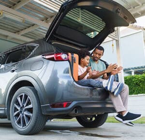 Father and son sitting in truck of car clapping and playing with one another.