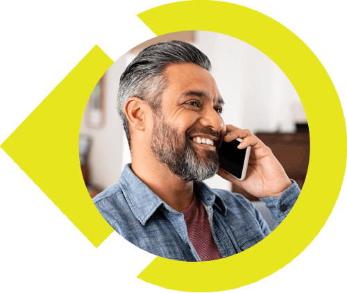 Man with grey hair and beard talking on cell phone and smiling.
