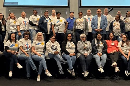 Group of men and women sitting and standing on stage posing for photo.