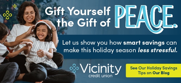 A family of three joyfully plays, with festive decor in the background. Text reads, "Gift Yourself the Gift of PEACE" promoting holiday savings at Vicinity Credit Union.