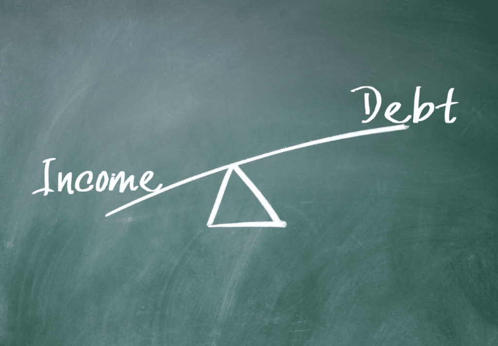 Seesaw showing "Debt" outweighing "Income" on a chalkboard